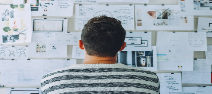 man inspecting wall with drawings and tables on it